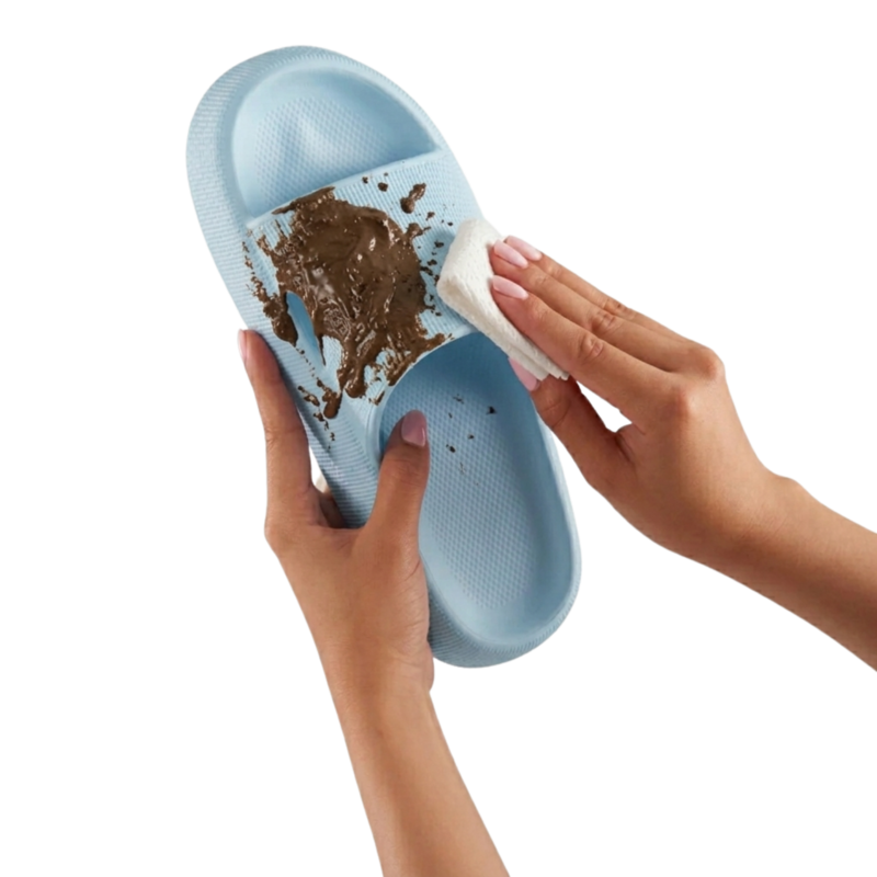 Hände reinigen einen hellblauen Slappys - Original Badeschuh mit einem weißen Tuch von braunem Schmutz.